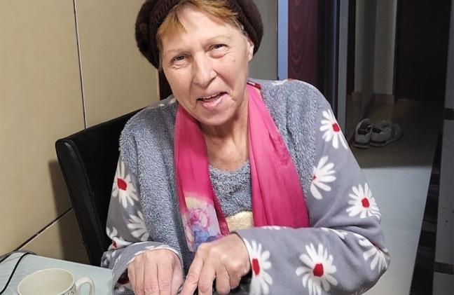 A woman from Romania smiles in her kitchen